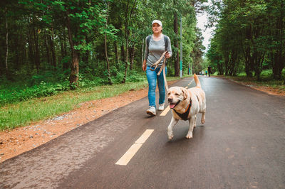 Portrait of woman with dog on road