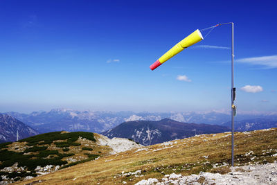 Windsock on mountain against blue sky