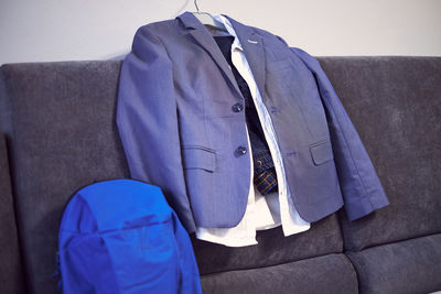 Midsection of man hanging on sofa against wall