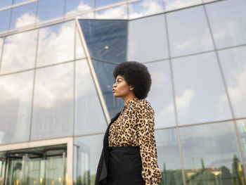 Young woman looking away while standing against wall