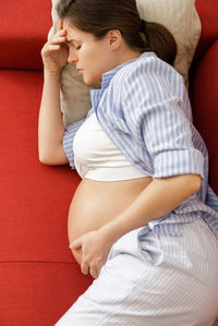 Rear view of baby boy sitting on sofa at home