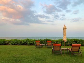 Chairs and table on beach against sky