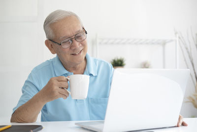 Midsection of man using mobile phone while sitting on table