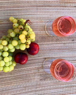 Directly above shot of grapes with plums and drink on table