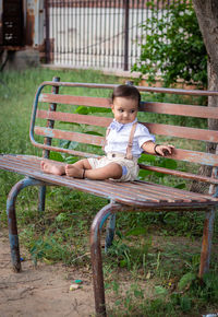 Portrait of boy sitting on bench at park