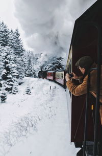 Man photographing snow field from train