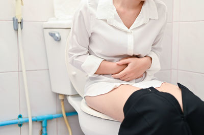 Midsection of woman sitting in bathroom