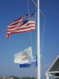 Low angle view of flags on pole against blue sky