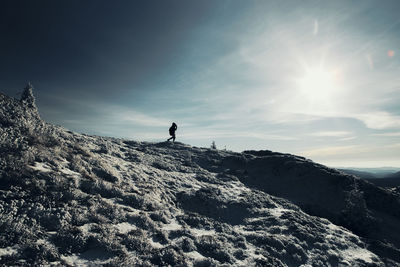 Low angle view of man standing on mountain against sky