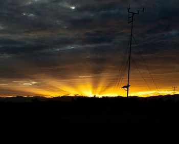 Silhouette landscape against dramatic sky during sunset