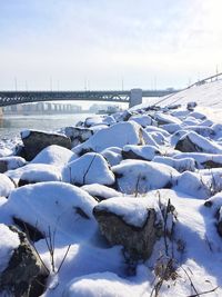 Snow covered stones against bridge and sky in background