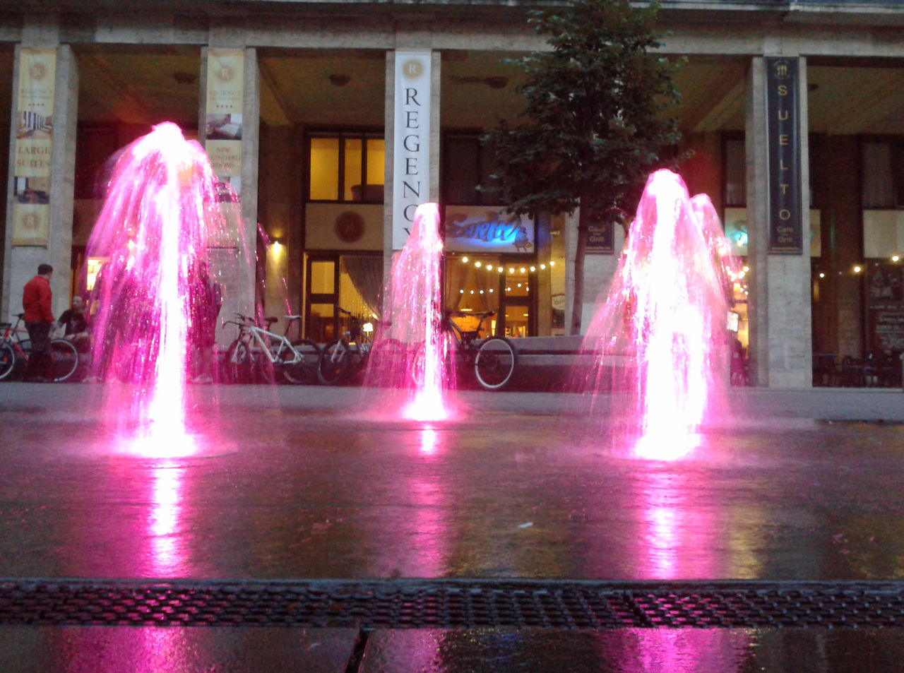 ILLUMINATED FOUNTAIN AGAINST BUILDINGS AT NIGHT