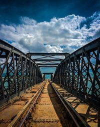 Railroad tracks over sea against cloudy sky