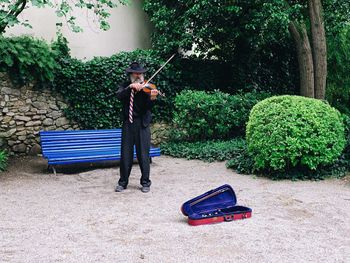 Man with umbrella on bench against plants