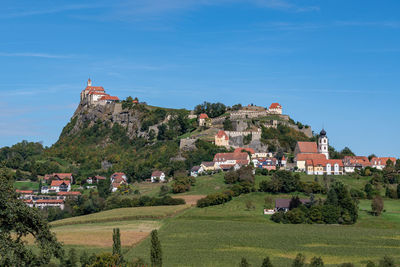 Houses by trees and buildings against sky