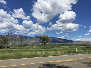 Road leading towards mountains against cloudy sky