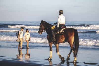 Full length of men on beach against sky