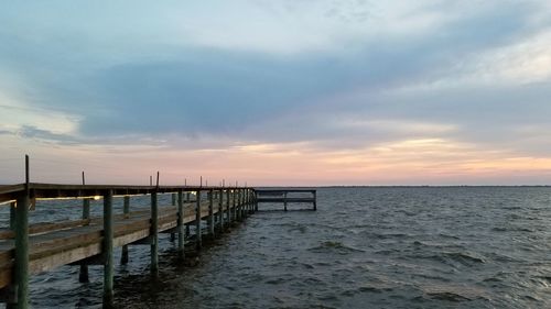 Pier over sea against sky during sunset