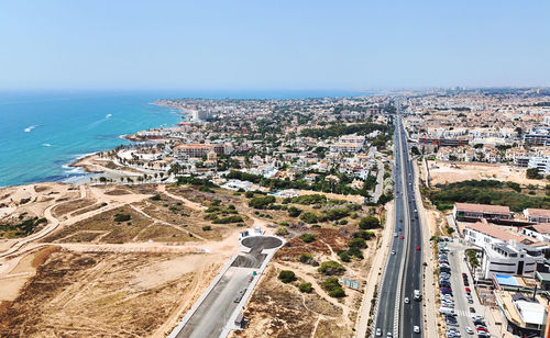 High angle view of townscape by sea against clear sky