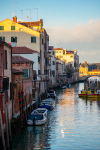 Boats moored in canal by buildings in city
