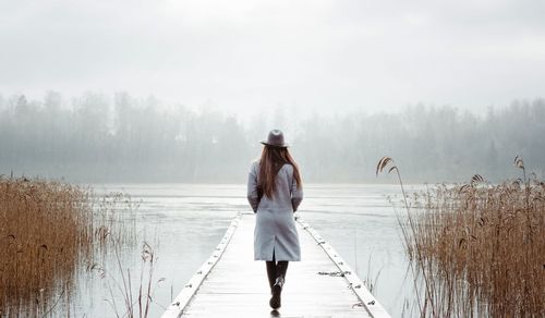 Woman walking alone thinking by the sea in winter on a jetty