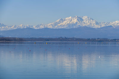 Scenic view of lake by snowcapped mountains against sky