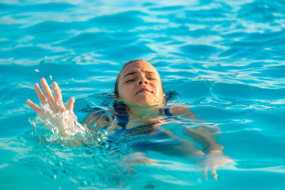 Cute girl drowning in swimming pool