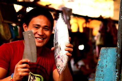 Man holding fish and chopper in hand