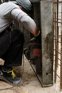 Builder with drill. man carpenter twists a screw into wooden plank with an electric screwdriver