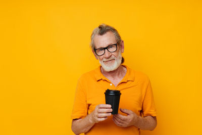 Young woman using mobile phone against yellow background