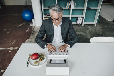 Senior businessman working at table next to fruit on plate