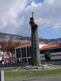 Statue in front of building against cloudy sky