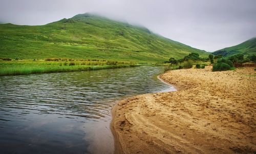  landscape scenery of sandy beach and green mountains  at connemara national park, ireland 