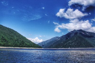 Scenic view of lake and mountains against blue sky