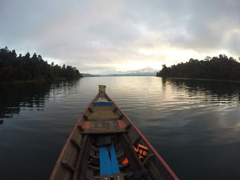 Cropped image of boat on river against cloudy sky