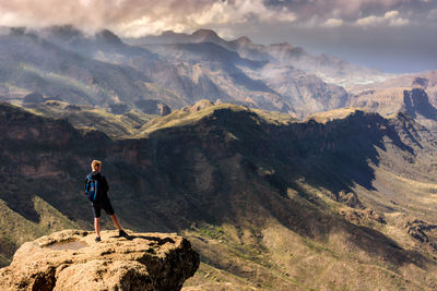 Man standing on rock against sky