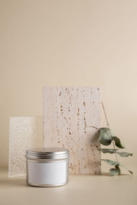 Face cream in a metal jar on a beige background with stone and glass. beauty and self care product