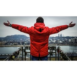 Rear view of man standing with arms outstretched standing against sky