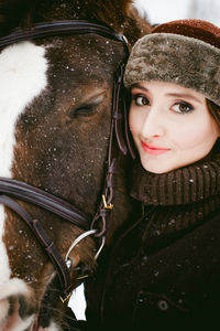 Close-up portrait of beautiful woman with horse during snowfall