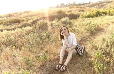 Portrait of young woman sitting on field