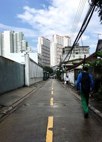 Rear view of man in city against sky