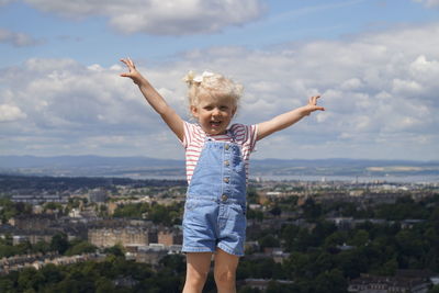 Girl standing against cloudy sky