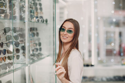 Portrait of smiling young woman wearing sunglasses at store