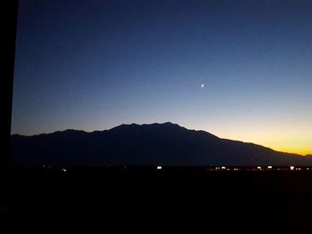 Silhouette of mountain range against blue sky