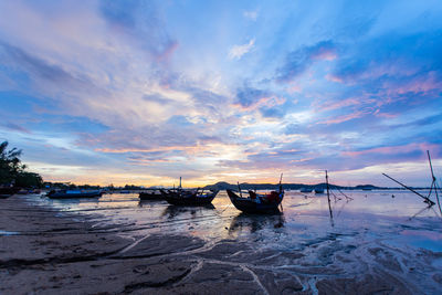 Boats moored on sea against sky during sunset