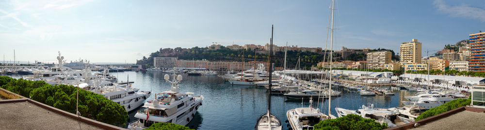 Sailboats moored on river amidst buildings in city against sky