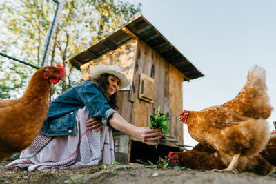 Happy middle aged woman on a private farm feeding chickens