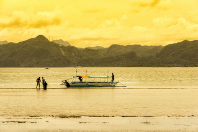 People on boat against sky during sunset