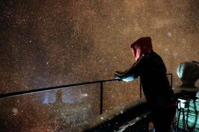 Man standing on pier over lake with star field reflection