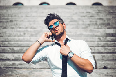 Midsection of man wearing sunglasses against wall
